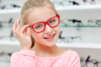 school eye exam | photo of young girl trying on red glasses