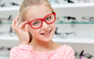 school eye exam | photo of young girl trying on red glasses