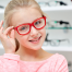 school eye exam | photo of young girl trying on red glasses