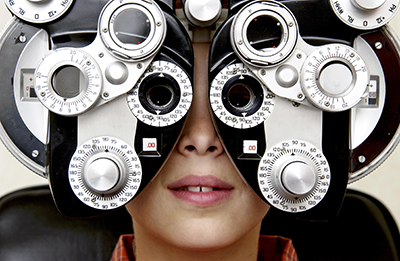 photo of boy looking through eye exam equipment