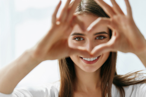 Beautiful Happy Woman Showing Love Sign Near Eyes. Young healthy eyes